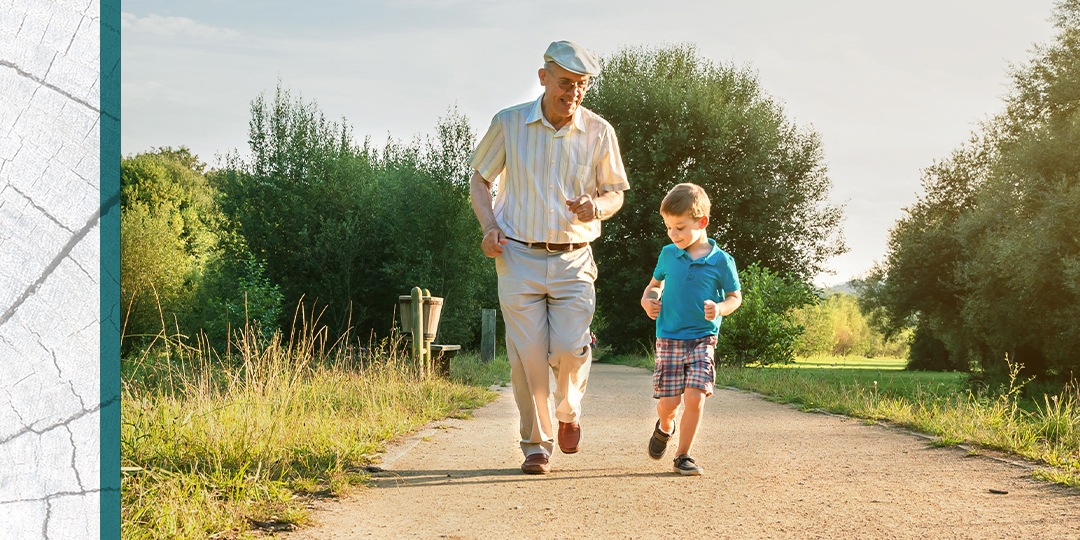 Senior and his grandson jog down an outdoor footpath