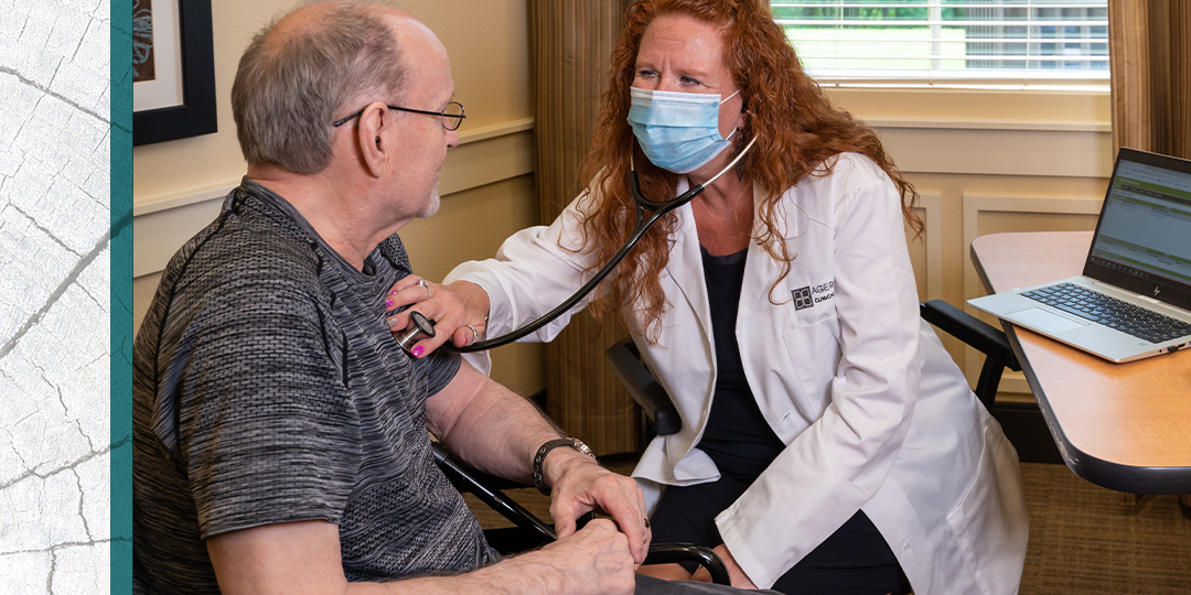 Masked physician assistant uses a stethoscope to listen to the heart of a senior.